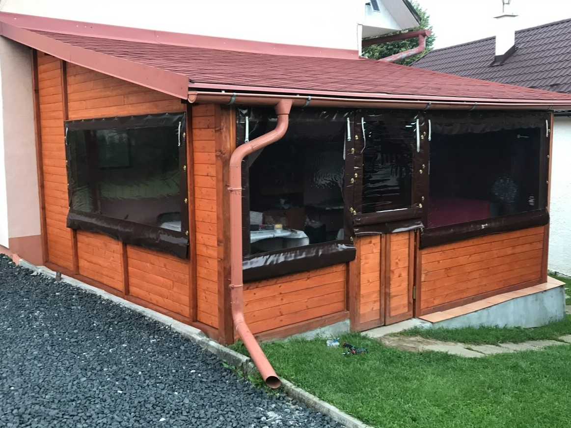Drevený záhradný altánok s veľkými oknami a červenou plechovou krytinou