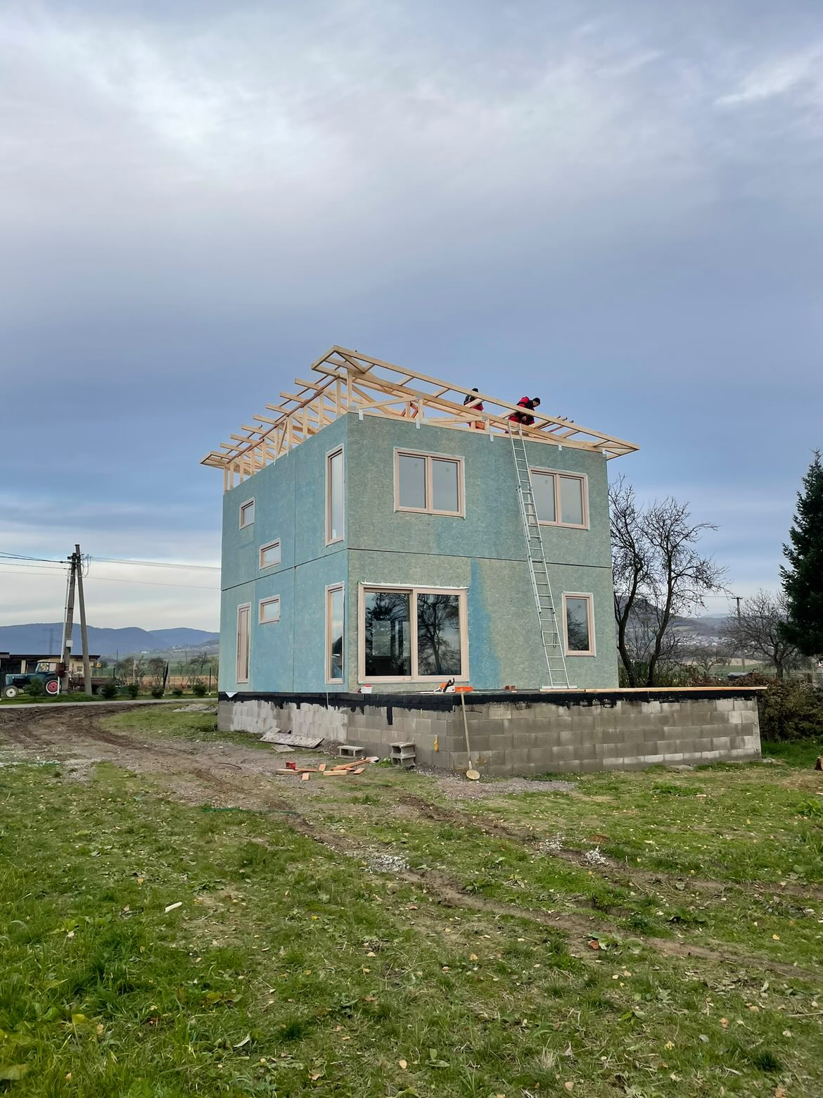 Moderný dvojpodlažný dom s tyrkysovou fasádou a drevenou strešnou konštrukciou